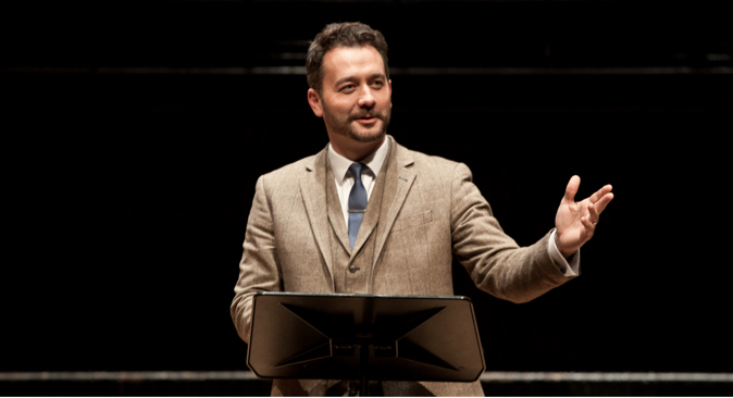 A man in a tan suit presenting