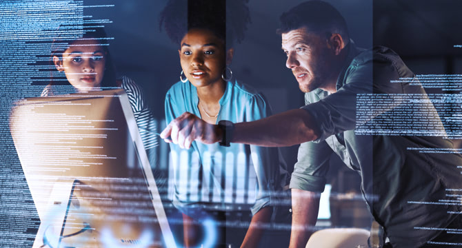 Three people working on a computer