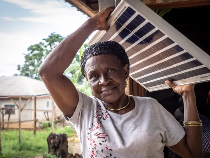 Photo showing a solar engineer, called 'solar mama', carrying a solar panel