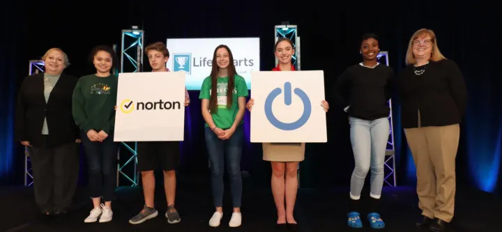 National LifeSmarts Championship attendees hold up a sign with a Norton logo on it